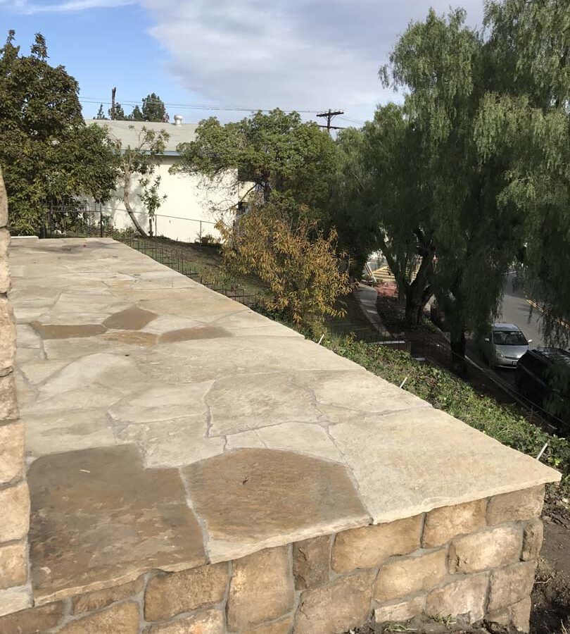 Stone veneer walls that match flagstone flatwork. Pacificland Constructors