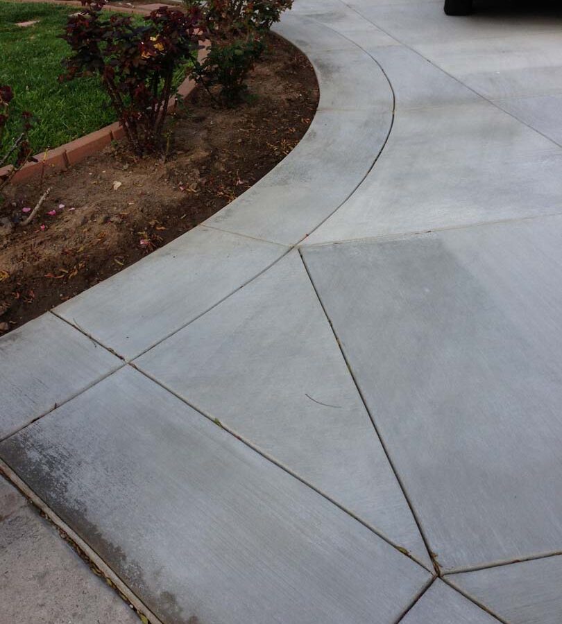 New gray concrete with diamond pattern and a ribbon around the perimeter. Surface is broom swept and has hand scorched joints. Pacificland Constructors