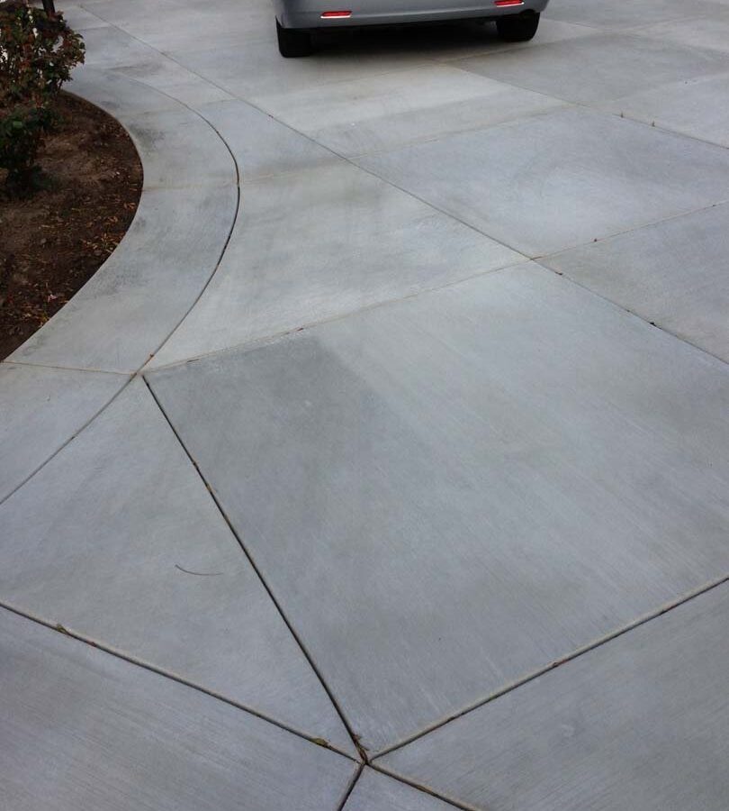 New gray concrete with diamond pattern and a ribbon around the perimeter. Surface is broom swept and has hand scorched joints. Pacificland Constructors