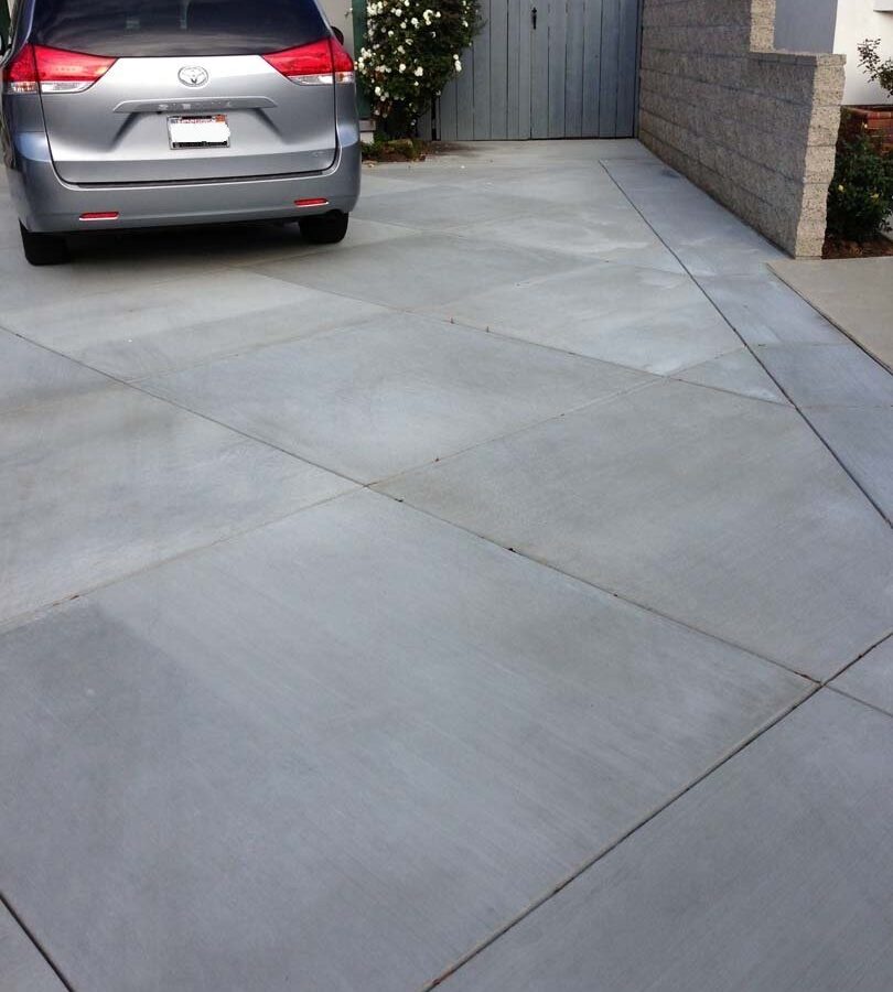 New gray concrete with diamond pattern and a ribbon around the perimeter. Surface is broom swept and has hand scorched joints. Pacificland Constructors